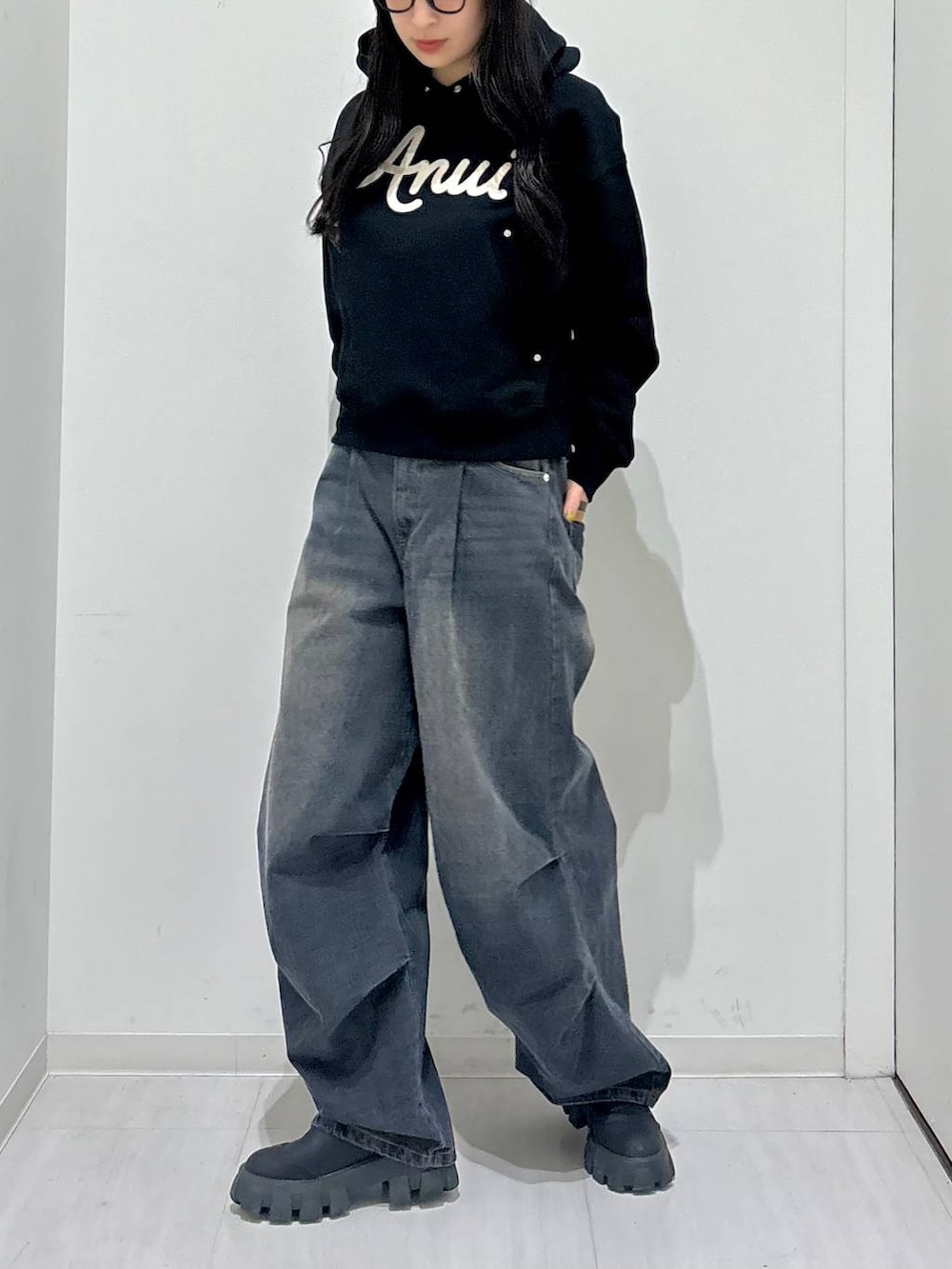 ブラック系のパーカー、ブラック系のブーツ、ブラック系のデニムパンツを着用したレディースの冬コーディネートの2枚目の写真