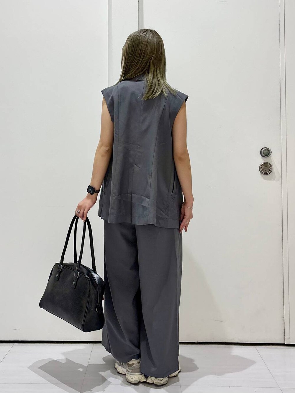 ブラック系のボストンバッグ、ホワイト系のタンクトップ、グレー系のスラックスを着用したレディースの春コーディネートの6枚目の写真