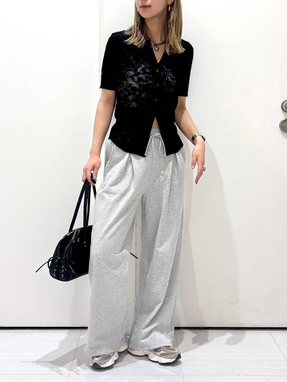 ブラック系のショルダーバッグ、ブラック系のシャツ/ブラウス、グレー系のスウェットパンツを着用したレディースの春コーディネートの4枚目の写真