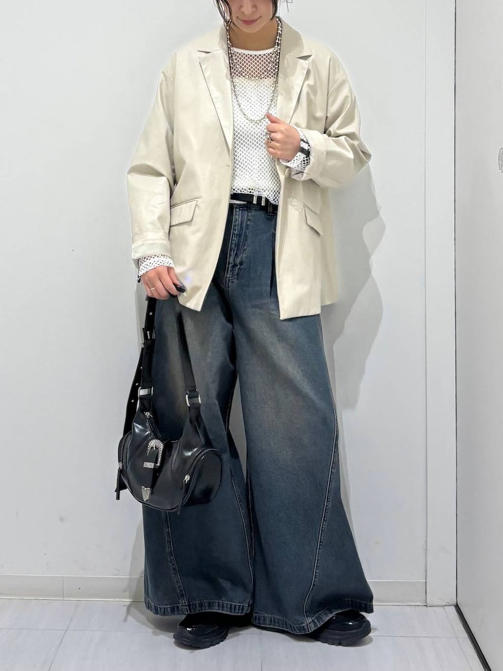 ブルー系のデニムパンツ、ブラック系のスニーカー、ホワイト系のTシャツ/カットソーを着用したレディースの春コーディネートの3枚目の写真