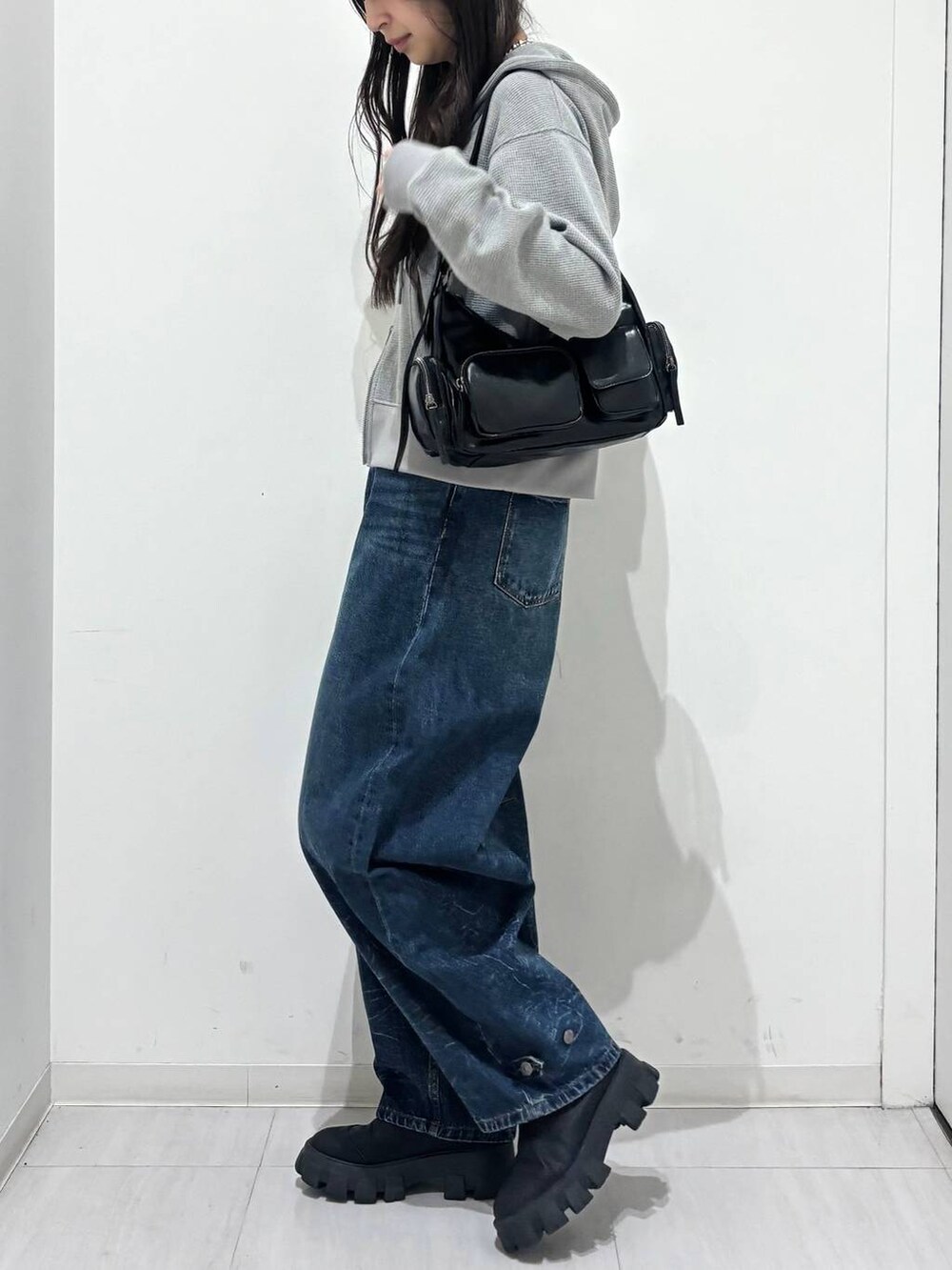 ブルー系のデニムパンツ、グレー系のパーカー、ブラック系のベルトを着用したレディースの冬コーディネートの3枚目の写真