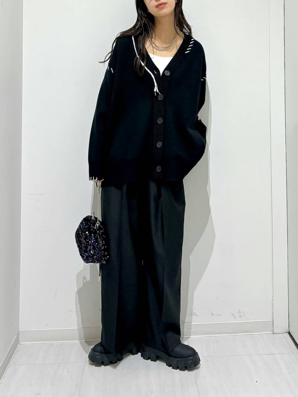 ホワイト系のタンクトップ、ブラック系のブーツ、ブラック系のカーディガン/ボレロを着用したレディースの秋コーディネートの5枚目の写真