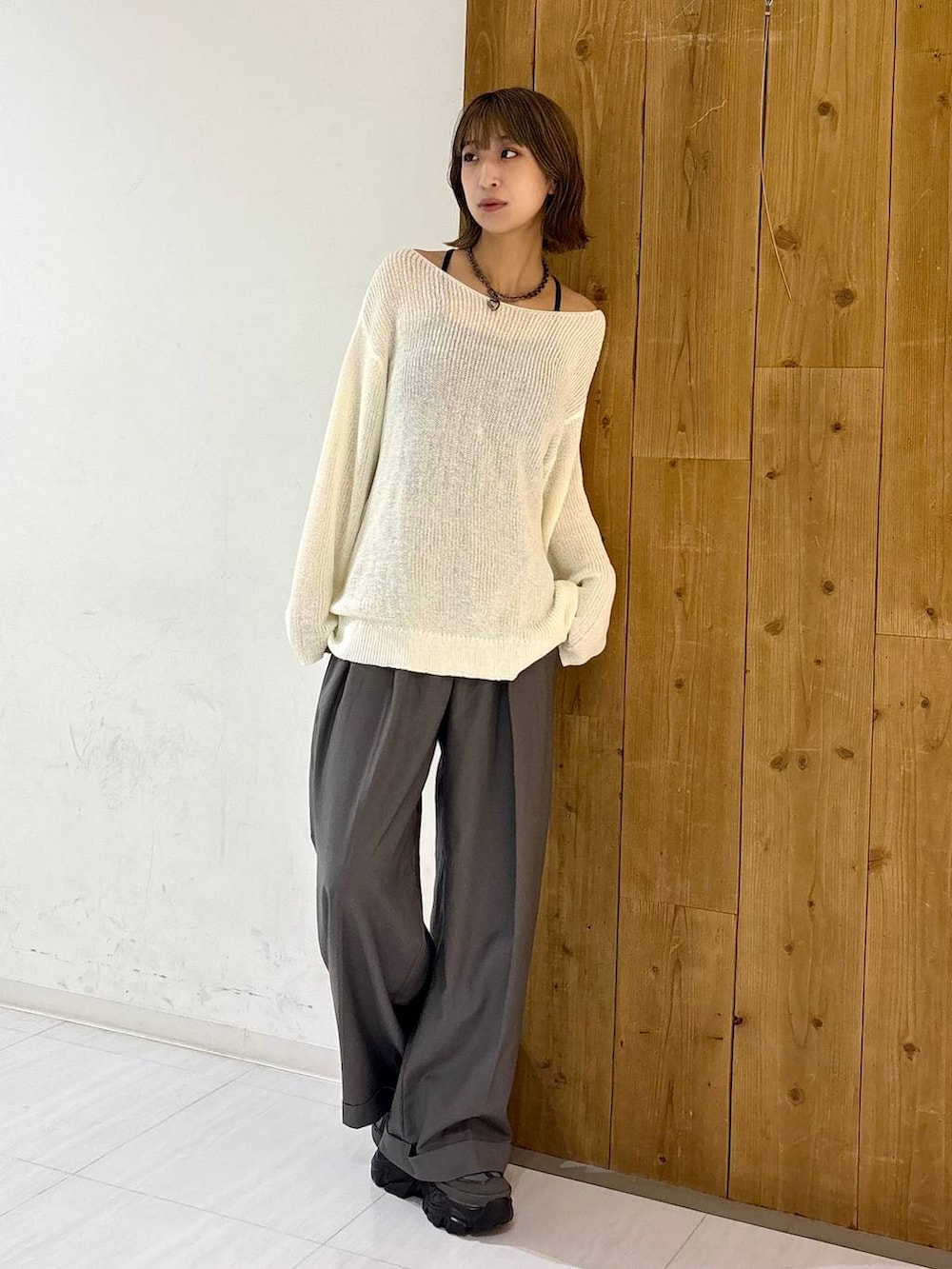 グレー系のスニーカー、ホワイト系のニット/セーター、グレー系のスラックスを着用したレディースの夏コーディネートの3枚目の写真