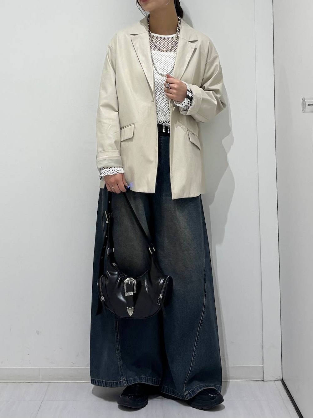 ブルー系のデニムパンツ、ブラック系のスニーカー、ホワイト系のTシャツ/カットソーを着用したレディースの春コーディネートの6枚目の写真