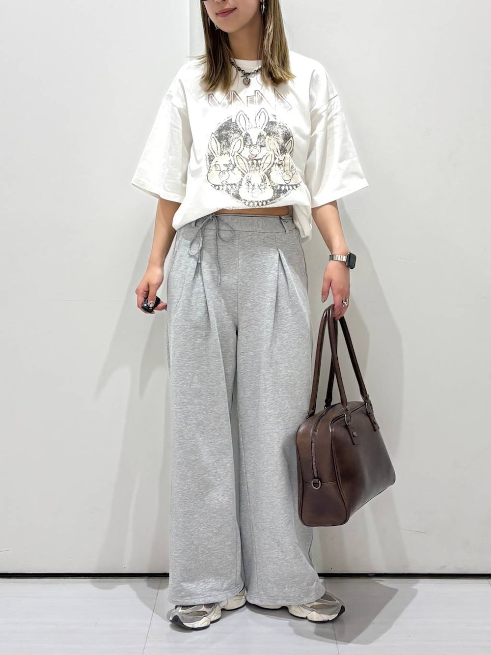ブラウン系のボストンバッグ、ホワイト系のTシャツ/カットソー、グレー系のスウェットパンツを着用したレディースの春コーディネートの2枚目の写真
