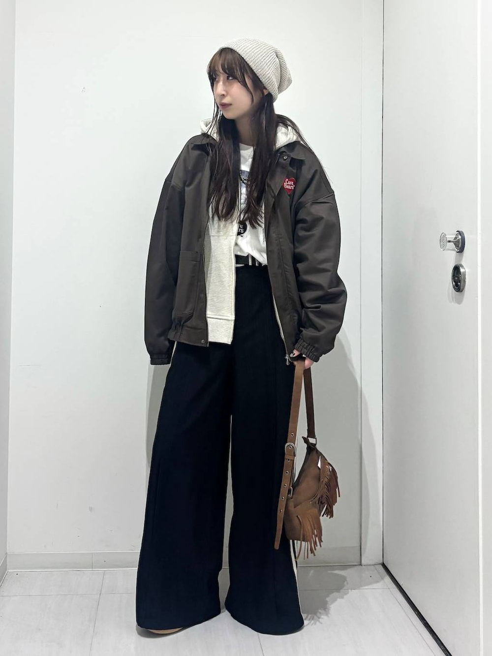 ベージュ系のショルダーバッグ、ブラック系のスラックス、ベージュ系のパーカーを着用したレディースの春コーディネートの2枚目の写真