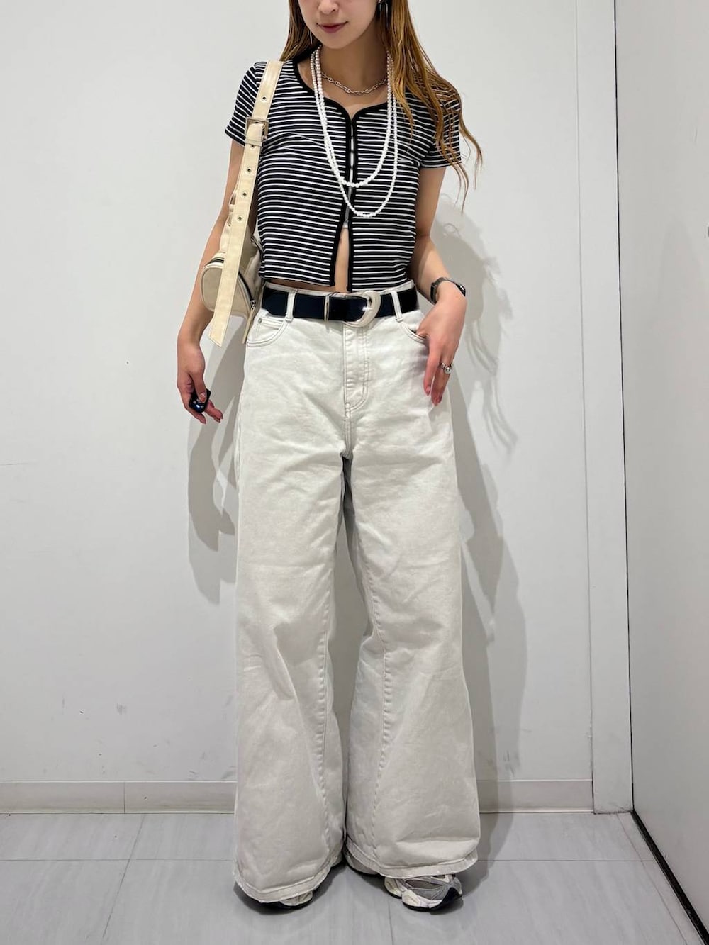 グレー系のデニムパンツ、ホワイト系のショルダーバッグ、ブラック系のTシャツ/カットソーを着用したレディースの春コーディネートの7枚目の写真