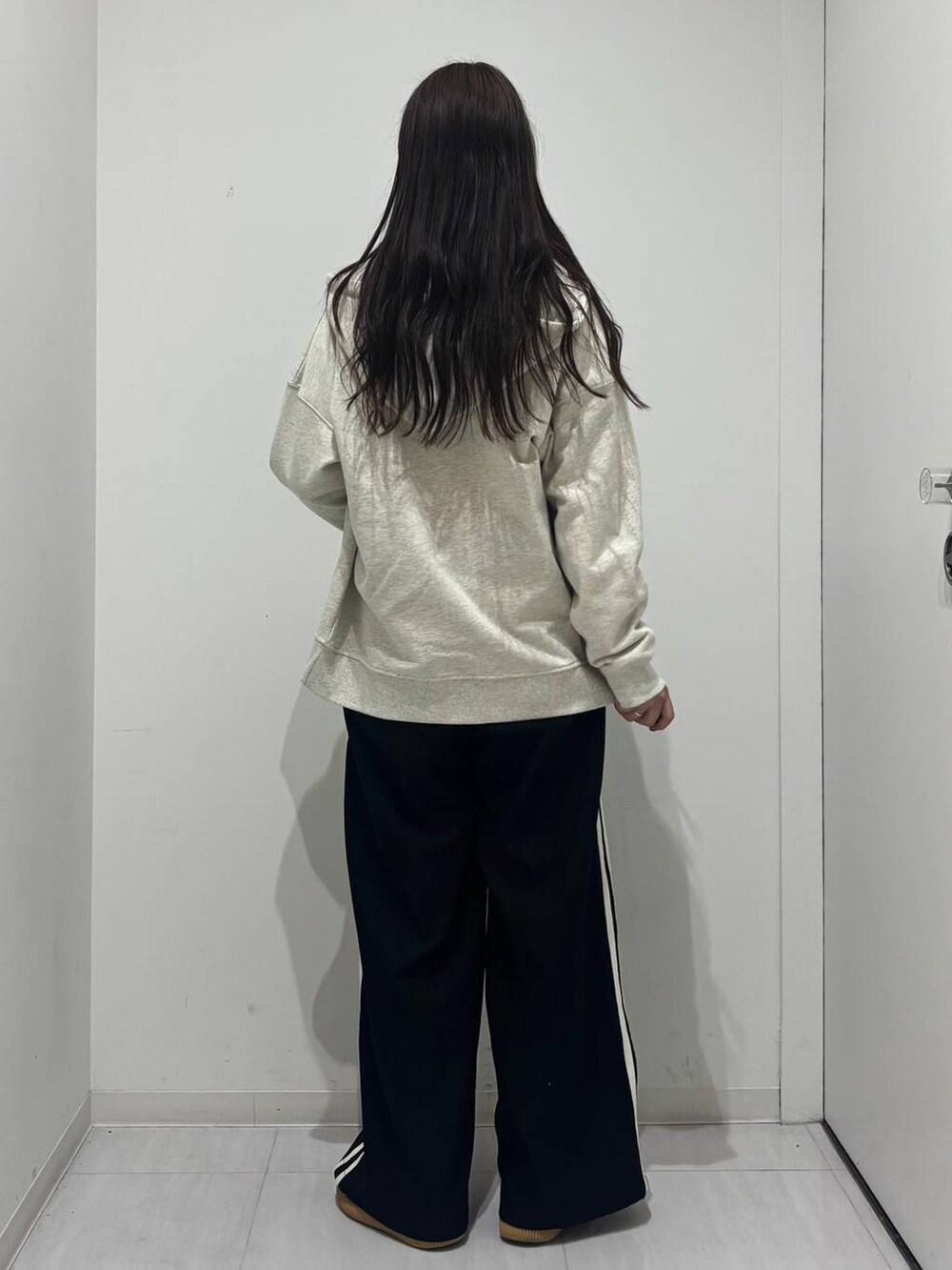 ホワイト系のショルダーバッグ、ブラック系のスラックス、ベージュ系のパーカーを着用したレディースの春コーディネートの3枚目の写真