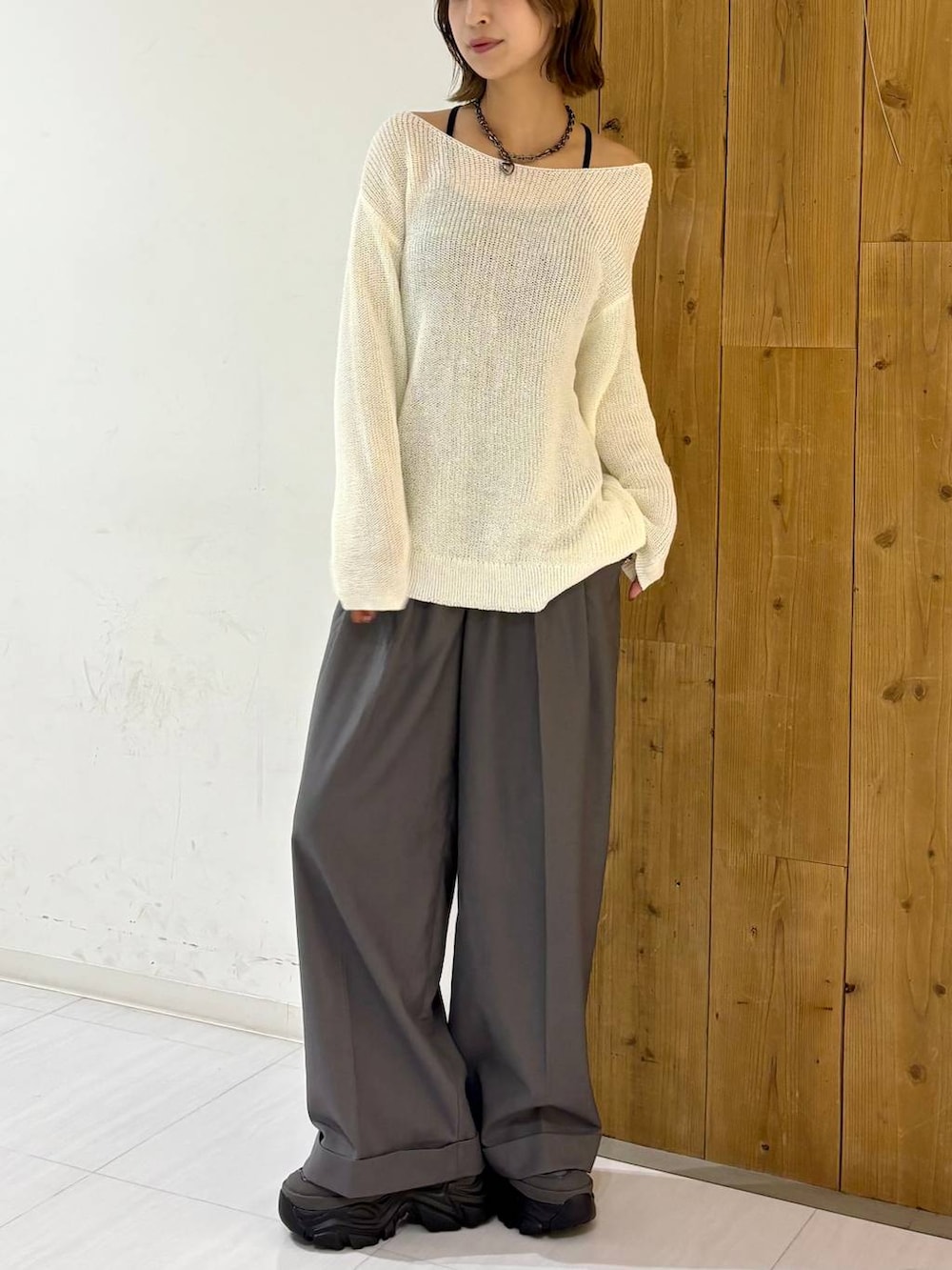 グレー系のスニーカー、ホワイト系のニット/セーター、グレー系のスラックスを着用したレディースの夏コーディネートの2枚目の写真