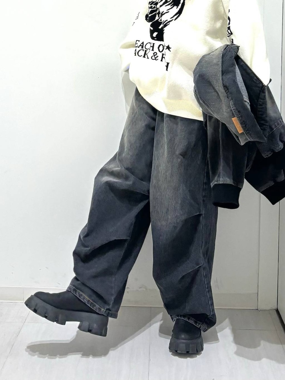 ホワイト系のニット/セーター、ブラック系のデニムジャケット、ブラック系のブーツを着用したレディースの冬コーディネートの4枚目の写真