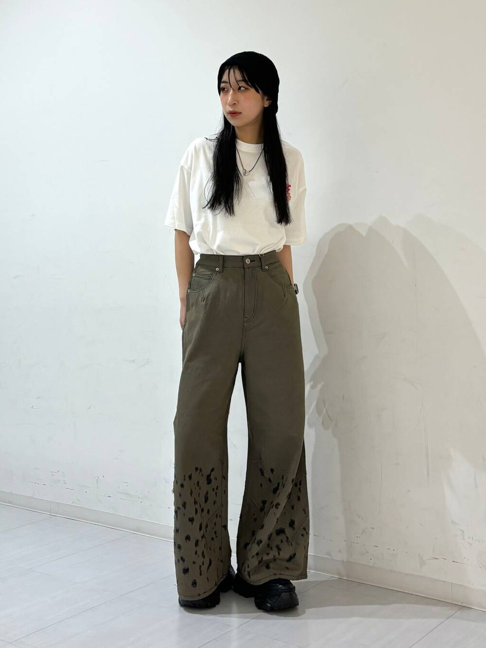 ブラック系のスニーカー、ホワイト系のTシャツ/カットソー、ブラック系のデニムパンツを着用したレディースの夏コーディネートの2枚目の写真