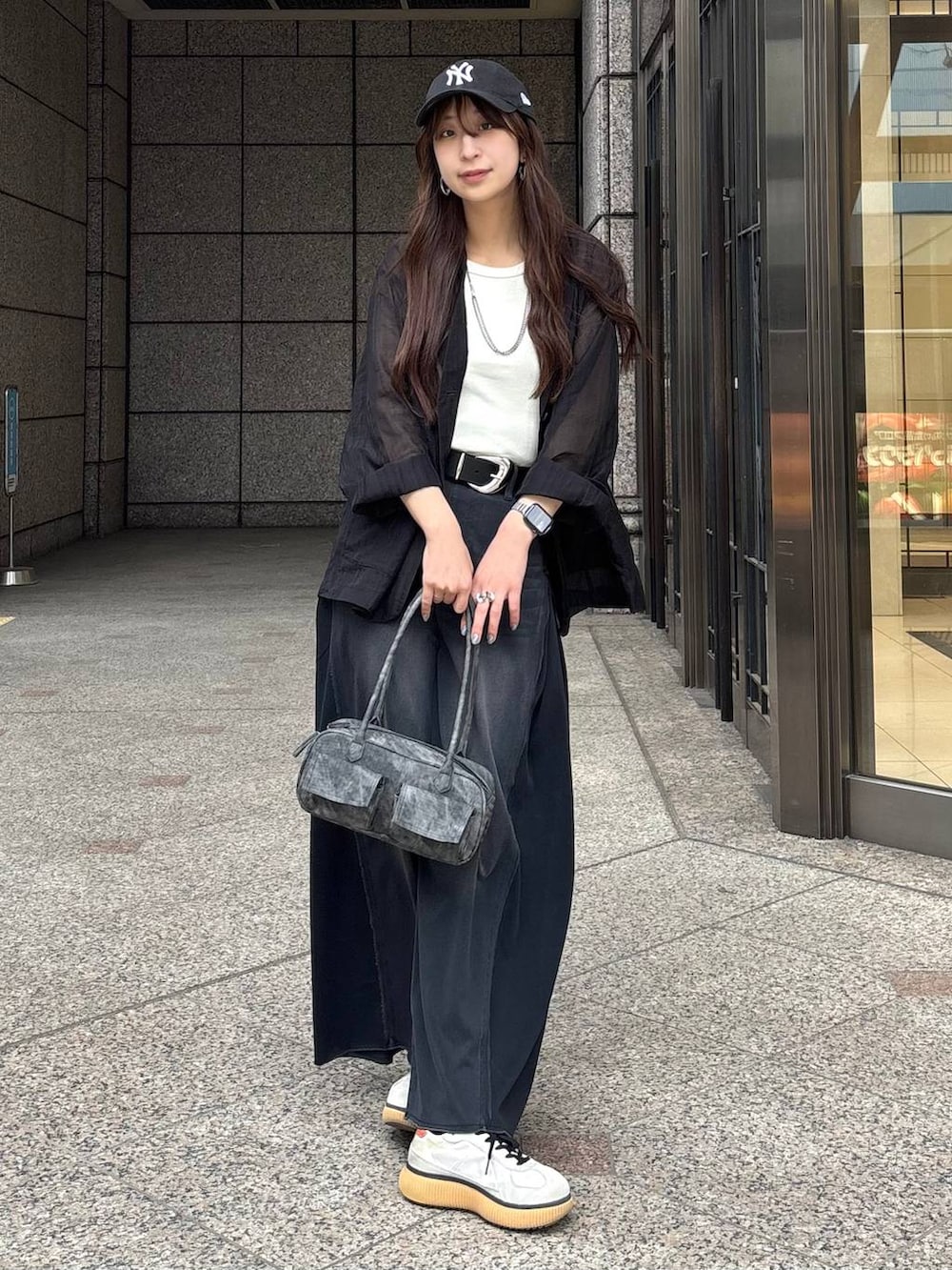 ブラック系のボストンバッグ、ホワイト系のタンクトップ、ブラック系のデニムパンツを着用したレディースの春コーディネートの5枚目の写真