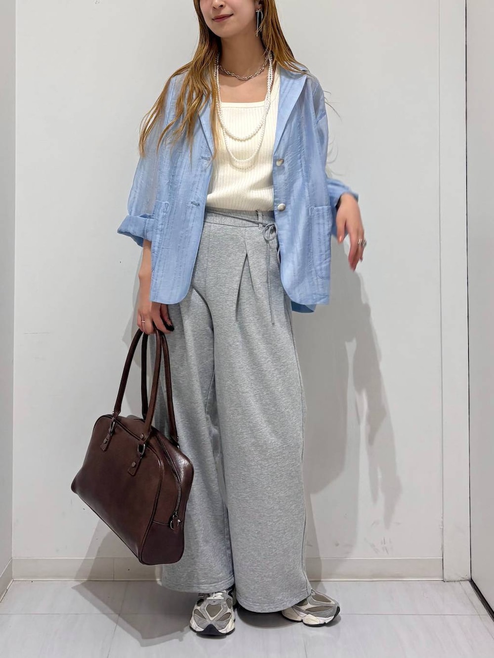 ブラウン系のボストンバッグ、ホワイト系のタンクトップ、ブルー系のテーラードジャケットを着用したレディースの春コーディネートの4枚目の写真