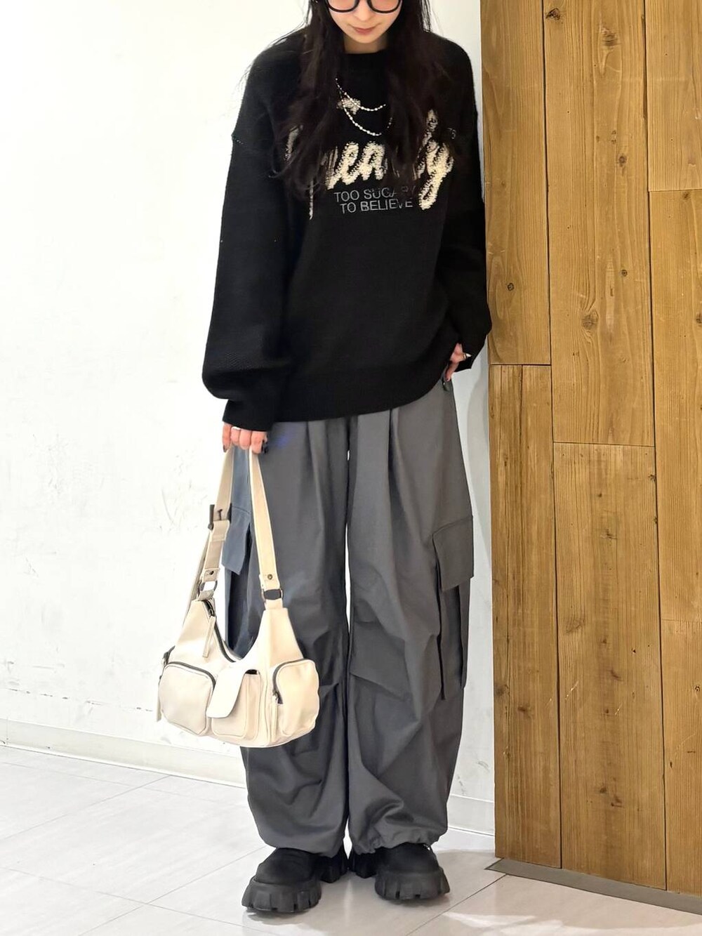 ホワイト系のショルダーバッグ、ブラック系のニット/セーター、グレー系のカーゴパンツを着用したレディースの冬コーディネートの2枚目の写真