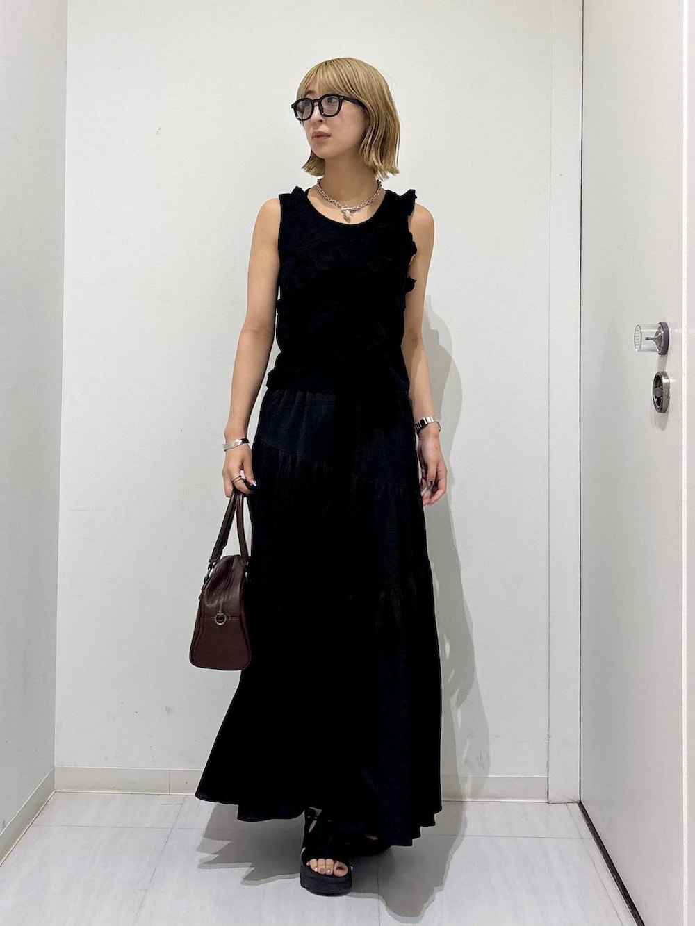 ブラウン系のショルダーバッグ、ブラック系のタンクトップ、ブラック系のスカートを着用したレディースの夏コーディネートの6枚目の写真