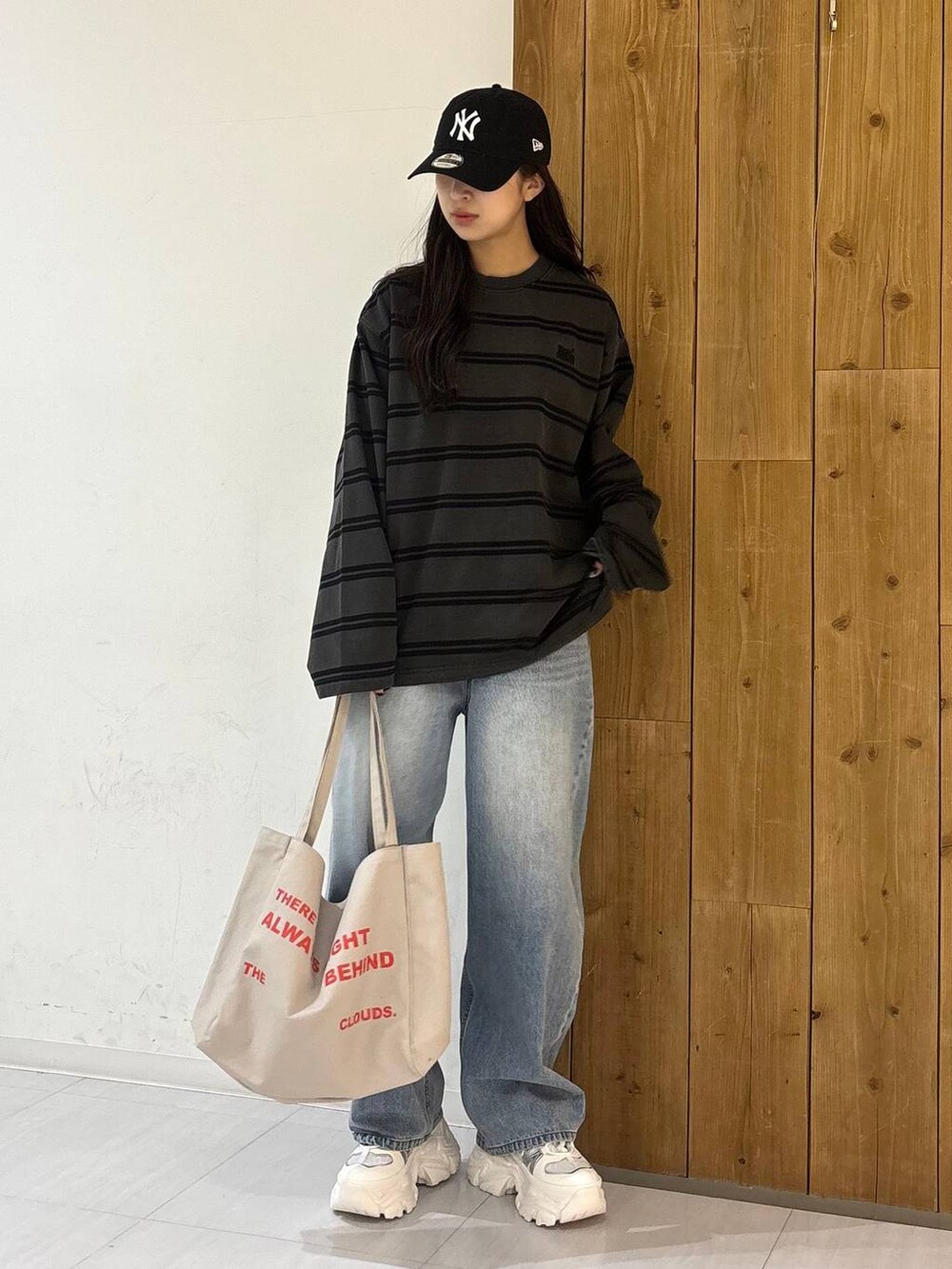 ホワイト系のスニーカー、ベージュ系のトートバッグ、ブルー系のデニムパンツを着用したレディースの冬コーディネートの2枚目の写真