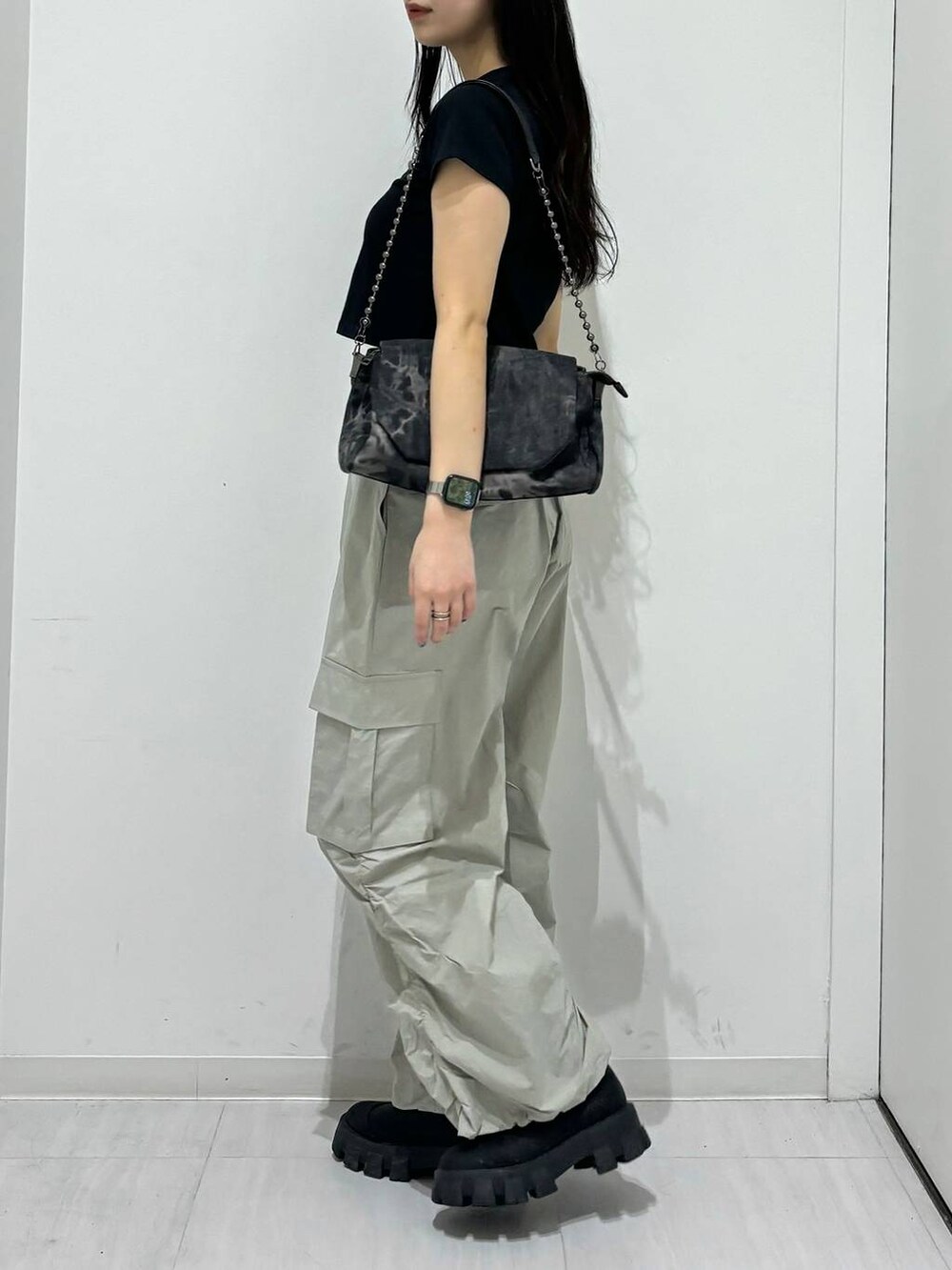 ブラック系のショルダーバッグ、ブラック系のTシャツ/カットソー、ブラック系のブーツを着用したレディースの春コーディネートの3枚目の写真