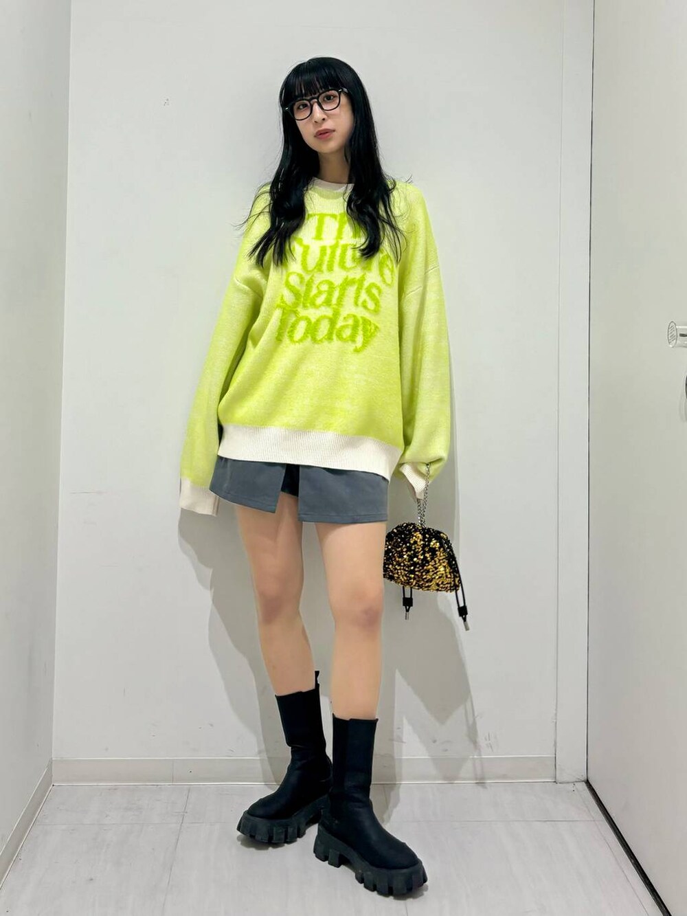 ブラック系のブーツ、ホワイト系のニット/セーター、ゴールド系のショルダーバッグを着用したレディースの冬コーディネートの5枚目の写真