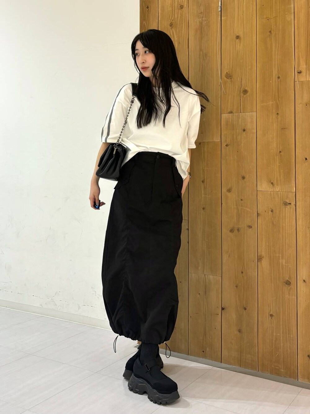 ブラック系のショルダーバッグ、ホワイト系のTシャツ/カットソー、ブラック系のスニーカーを着用したレディースの春コーディネートの6枚目の写真