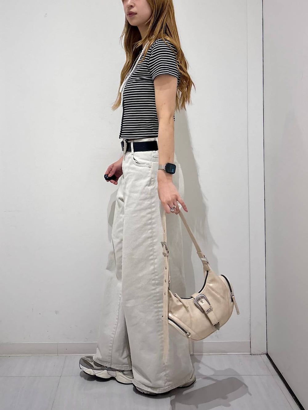 グレー系のデニムパンツ、ホワイト系のショルダーバッグ、ブラック系のTシャツ/カットソーを着用したレディースの春コーディネートの5枚目の写真