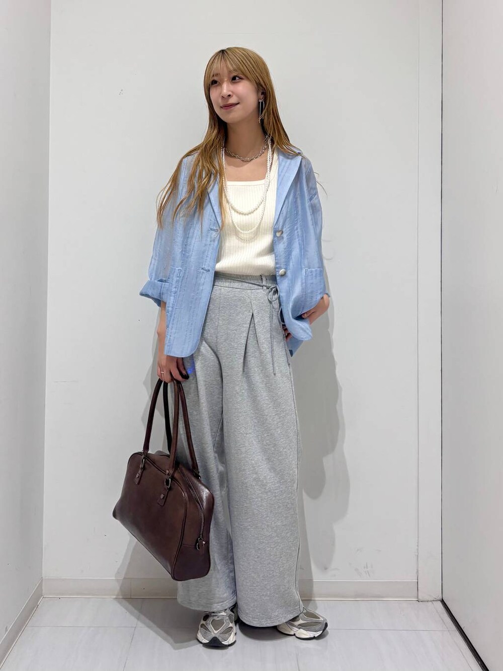 ブラウン系のボストンバッグ、ホワイト系のタンクトップ、ブルー系のテーラードジャケットを着用したレディースの春コーディネートの9枚目の写真