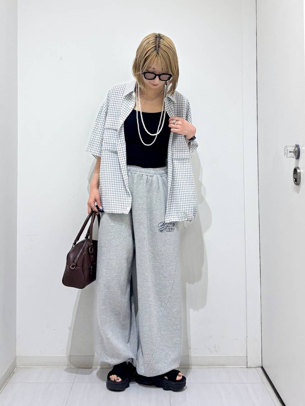 ブラウン系のショルダーバッグ、グレー系のスウェットパンツ、ホワイト系のシャツ/ブラウスを着用したレディースの夏コーディネートの3枚目の写真
