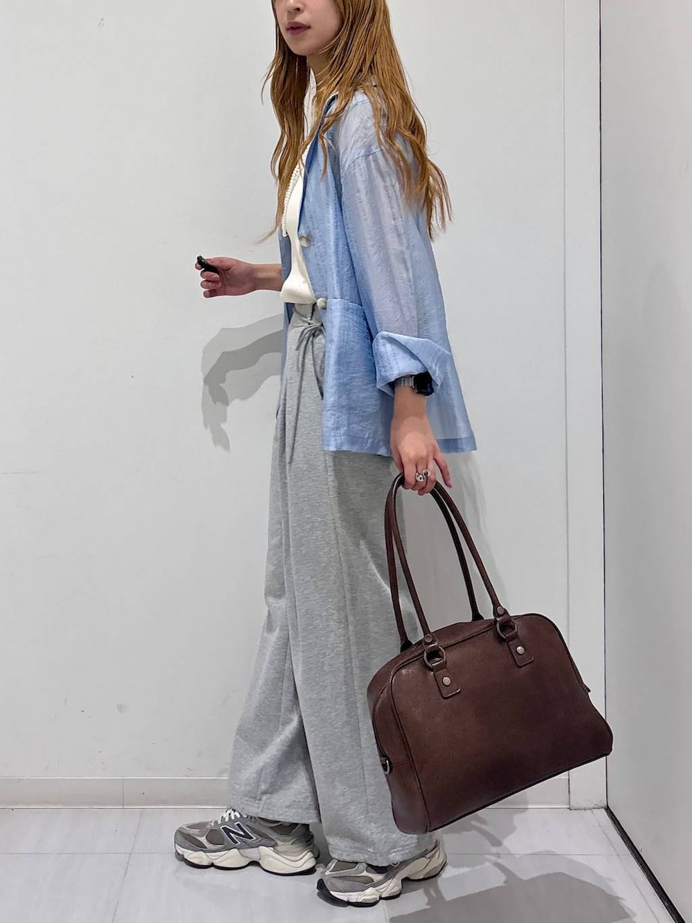 ブラウン系のボストンバッグ、ホワイト系のタンクトップ、ブルー系のテーラードジャケットを着用したレディースの春コーディネートの6枚目の写真