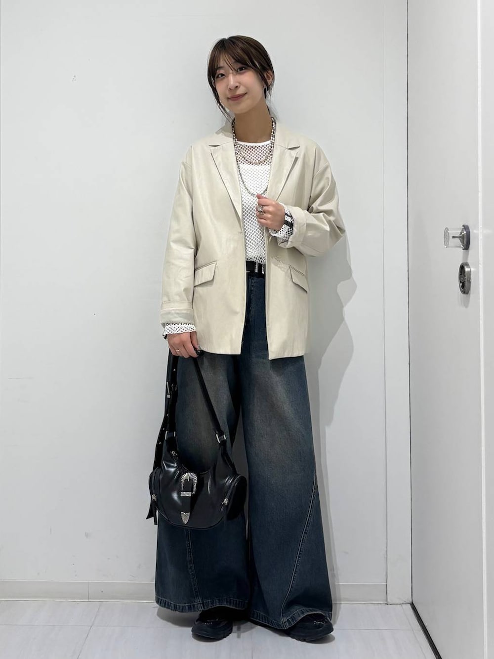 ブルー系のデニムパンツ、ブラック系のスニーカー、ホワイト系のTシャツ/カットソーを着用したレディースの春コーディネートの7枚目の写真