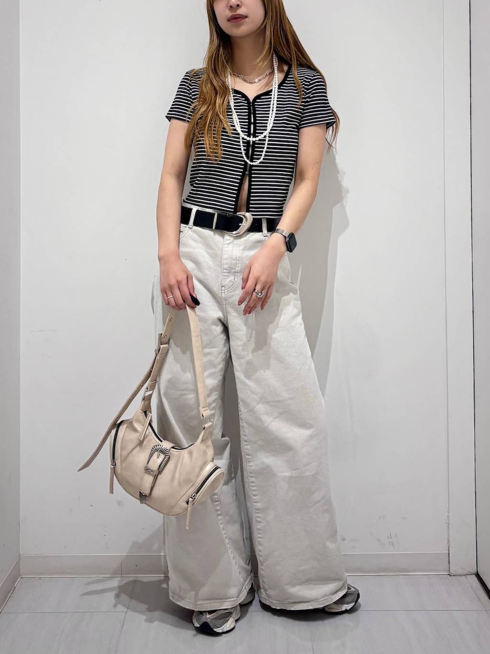 グレー系のデニムパンツ、ホワイト系のショルダーバッグ、ブラック系のTシャツ/カットソーを着用したレディースの春コーディネートの2枚目の写真