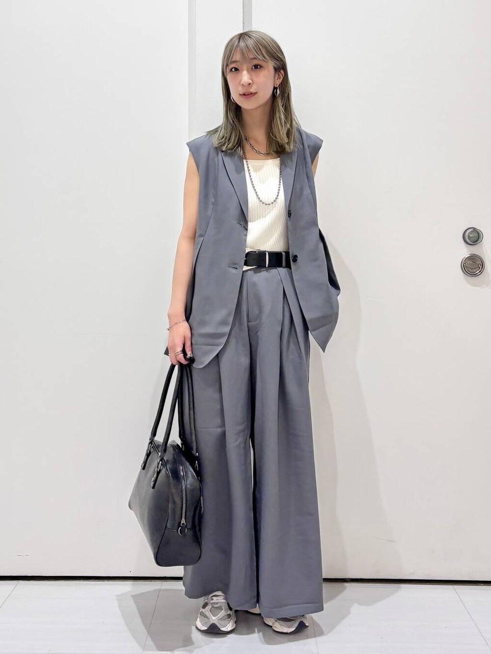 ブラック系のボストンバッグ、ホワイト系のタンクトップ、グレー系のスラックスを着用したレディースの春コーディネートの7枚目の写真