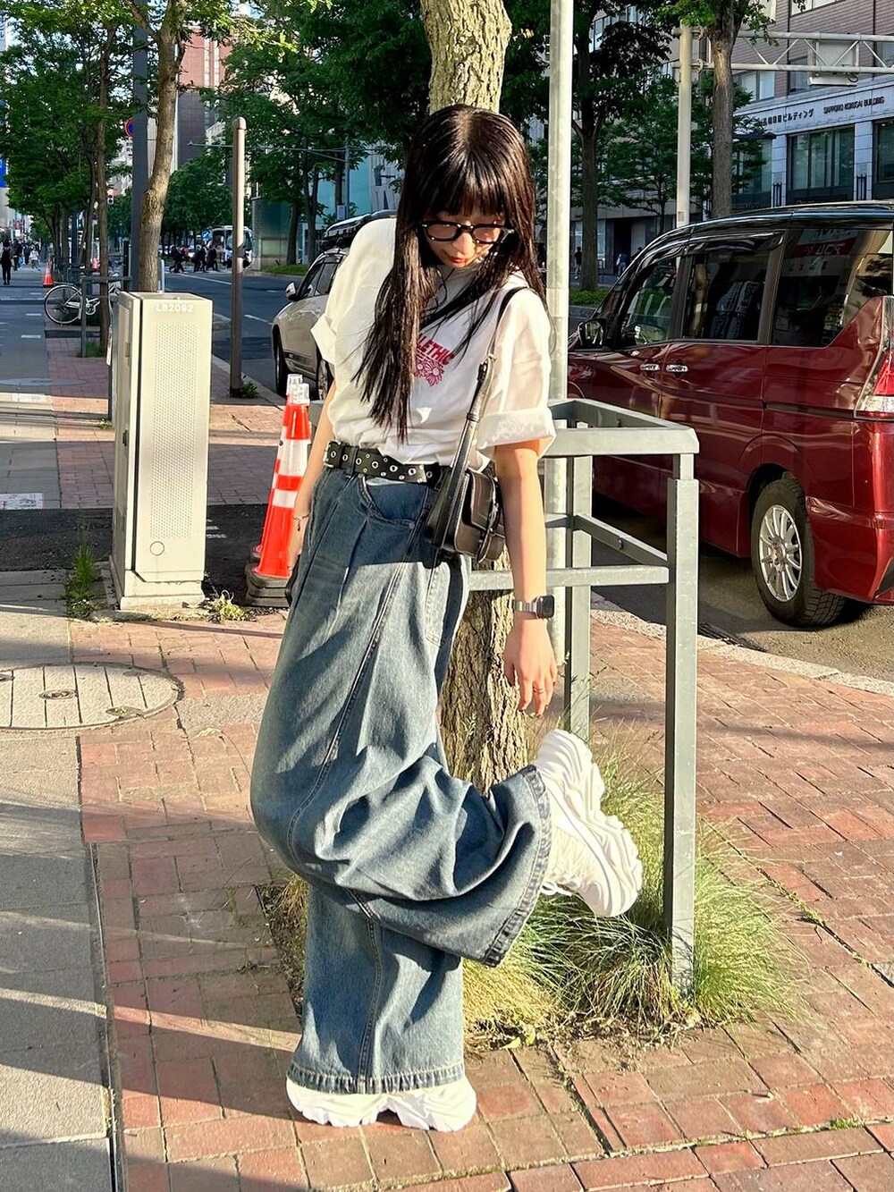 ホワイト系のスニーカー、ブラック系のハンドバッグ、ブルー系のデニムパンツを着用したレディースの夏コーディネートの5枚目の写真