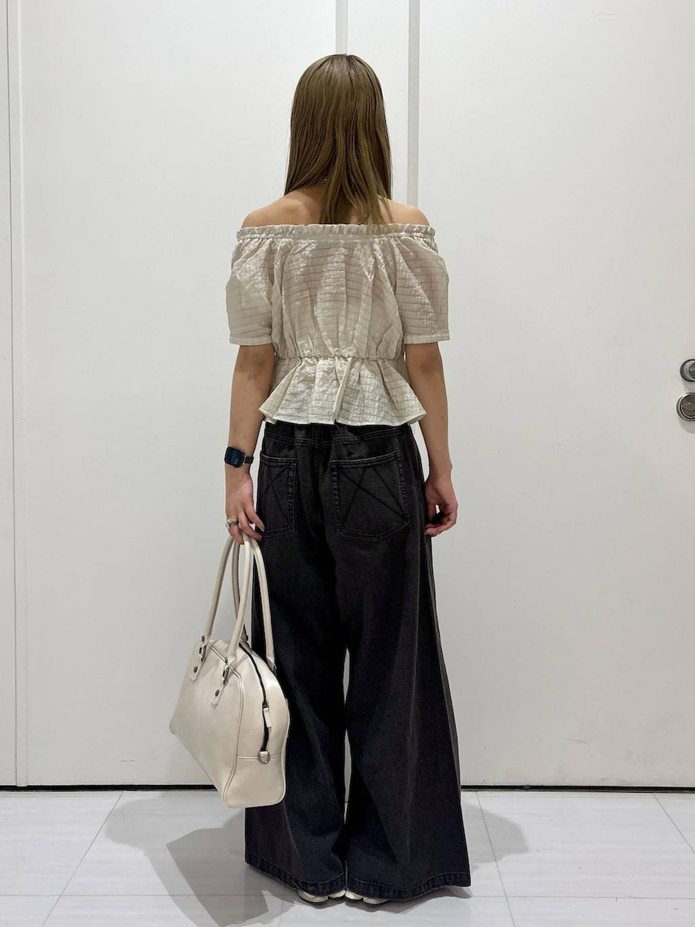 ブラック系のデニムパンツ、ホワイト系のボストンバッグ、ホワイト系のネックレスを着用したレディースの夏コーディネートの4枚目の写真