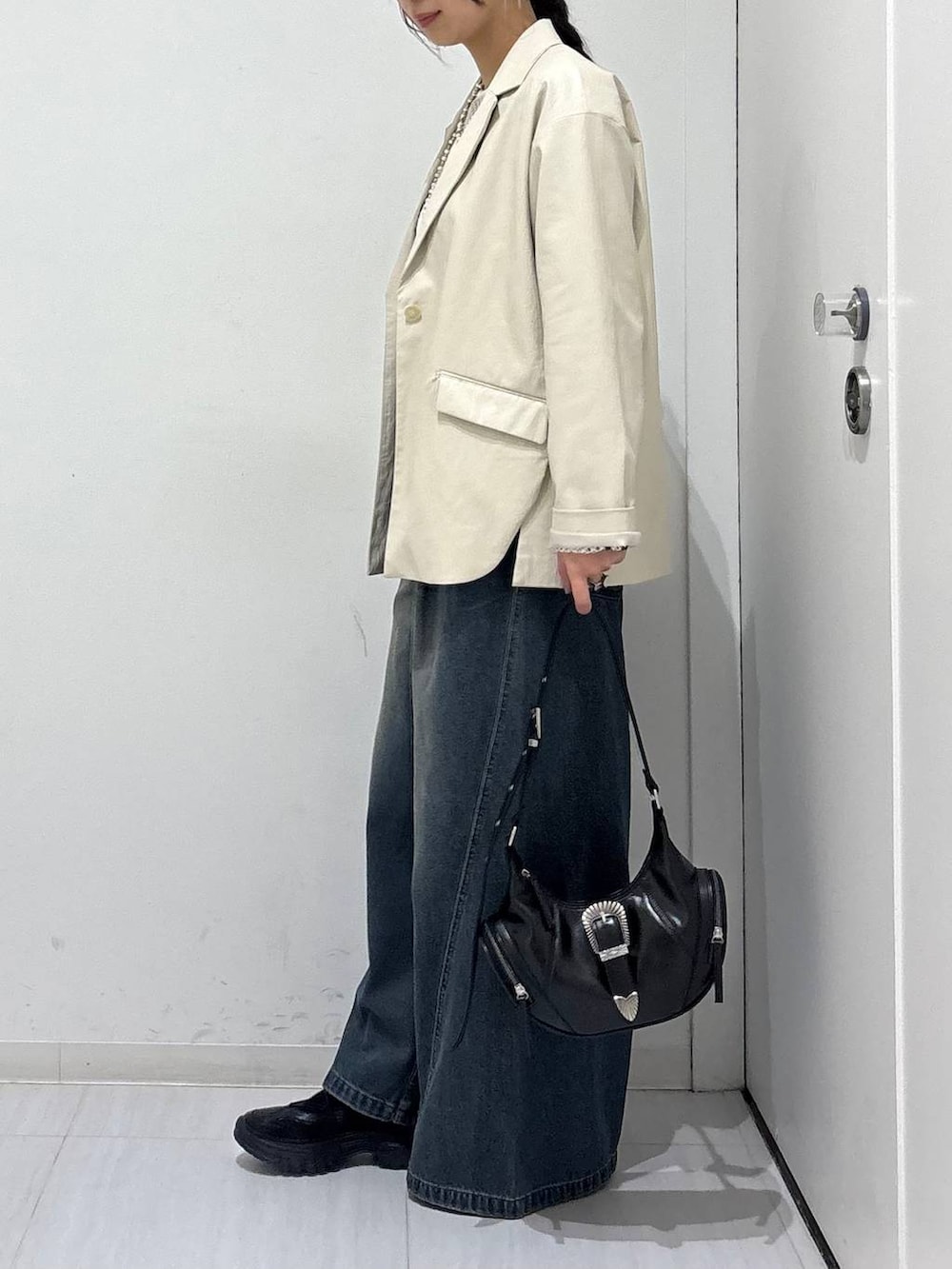 ブルー系のデニムパンツ、ブラック系のスニーカー、ホワイト系のTシャツ/カットソーを着用したレディースの春コーディネートの4枚目の写真