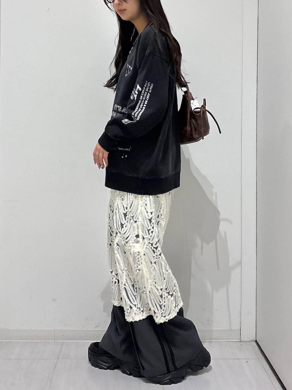 ブラック系のスニーカー、グレー系のスウェット、ブラウン系のショルダーバッグを着用したレディースの冬コーディネートの2枚目の写真