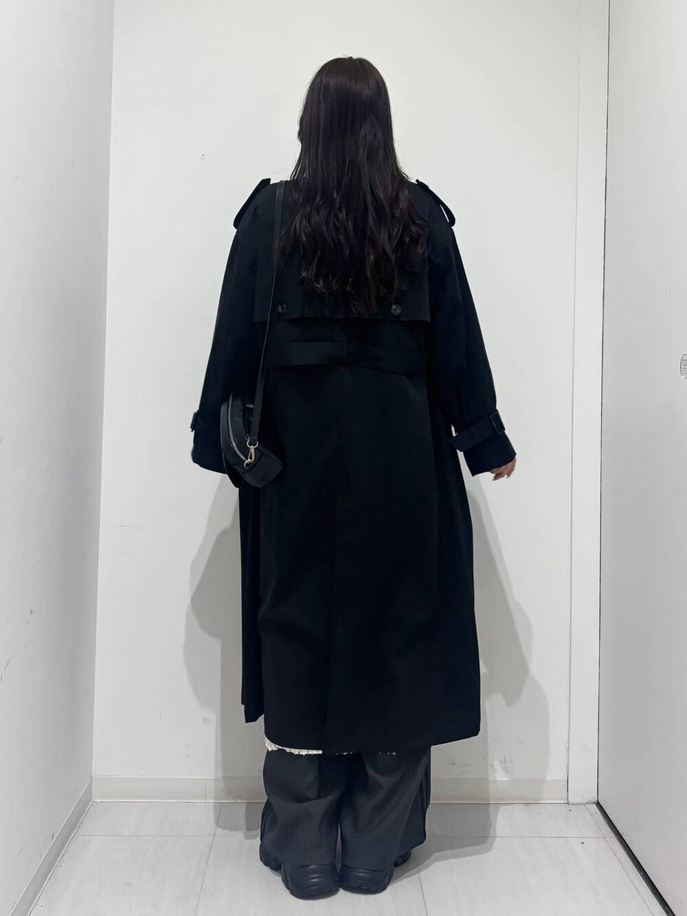 ブラック系のスニーカー、ブラック系のトレンチコート、ホワイト系のワンピースを着用したレディースの冬コーディネートの3枚目の写真