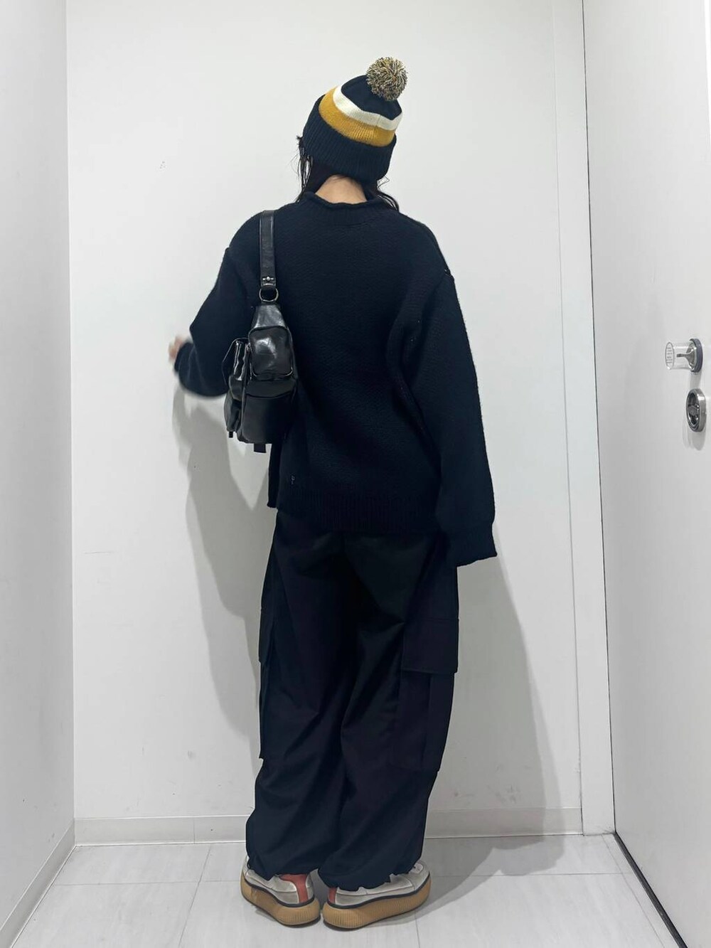 ブラック系のショルダーバッグ、ブラック系のカーゴパンツ、ブルー系のニット/セーターを着用したレディースの秋コーディネートの4枚目の写真