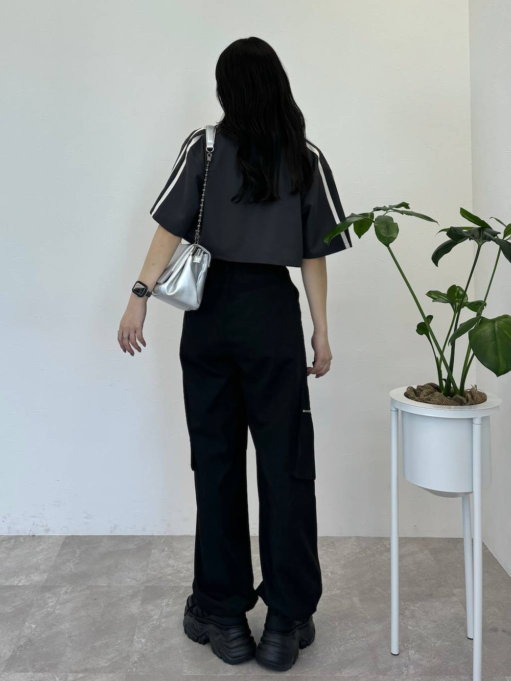 シルバー系のショルダーバッグ、ブラック系のスニーカー、ブラック系のカーゴパンツを着用したレディースの春コーディネートの3枚目の写真