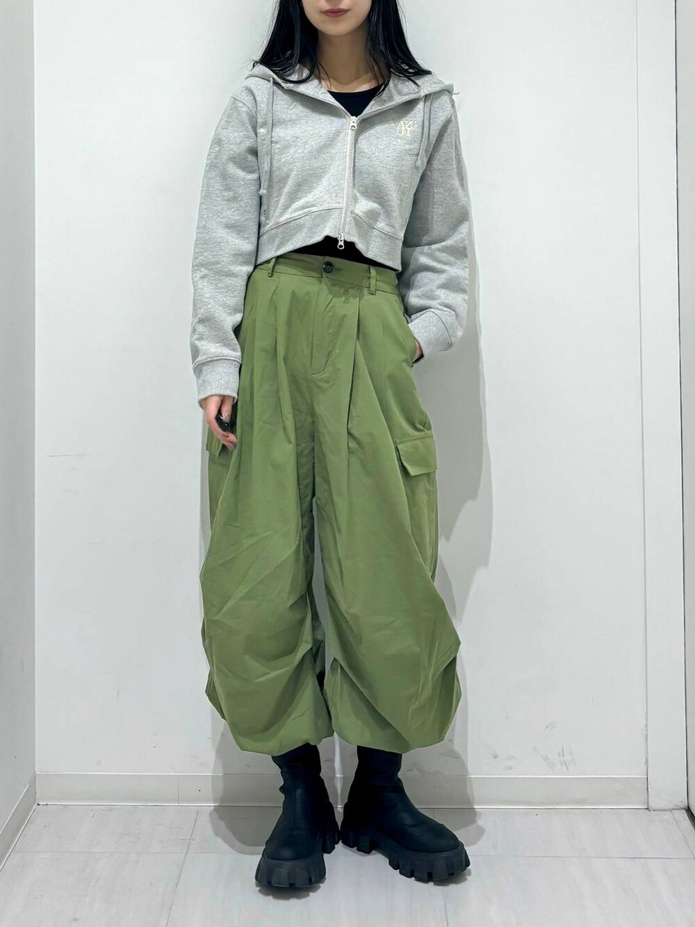 グレー系のパーカー、ブラック系のブーツ、グリーン系のその他パンツを着用したレディースの冬コーディネートの2枚目の写真