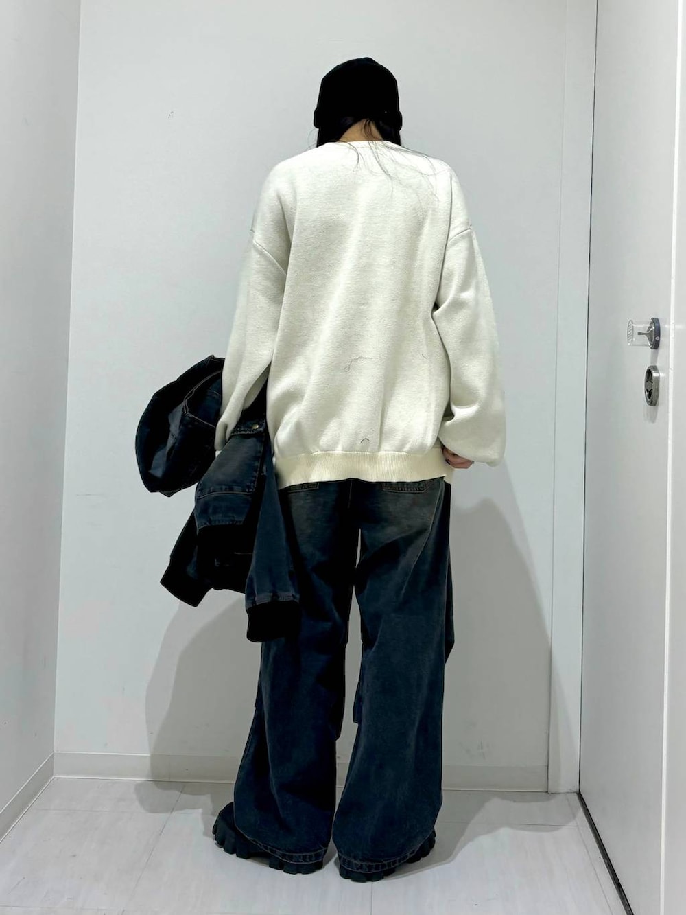 ホワイト系のニット/セーター、ブラック系のデニムジャケット、ブラック系のブーツを着用したレディースの冬コーディネートの7枚目の写真