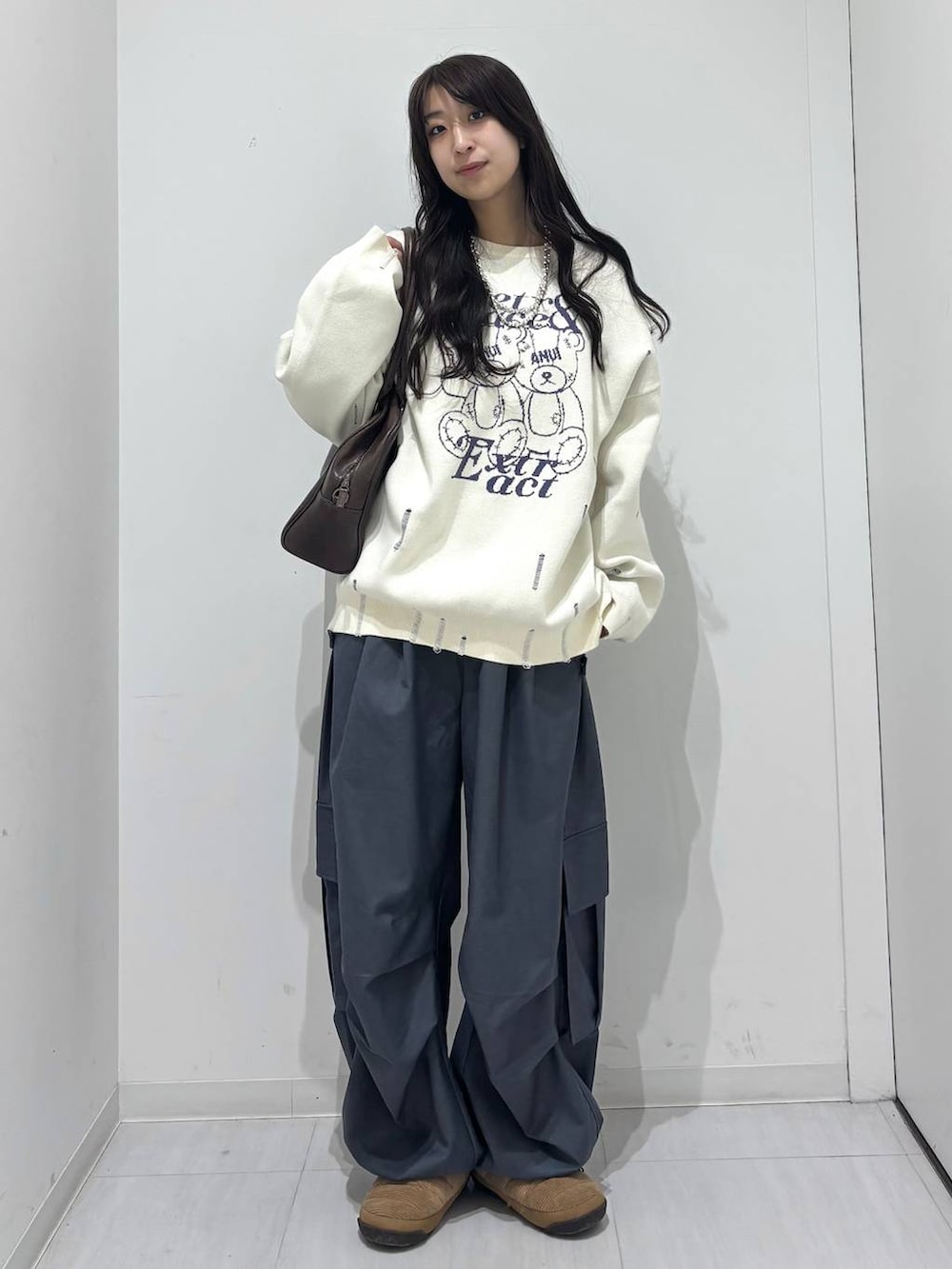 グレー系のカーゴパンツ、ホワイト系のニット/セーター、ブラウン系のボストンバッグを着用したレディースの冬コーディネートの2枚目の写真