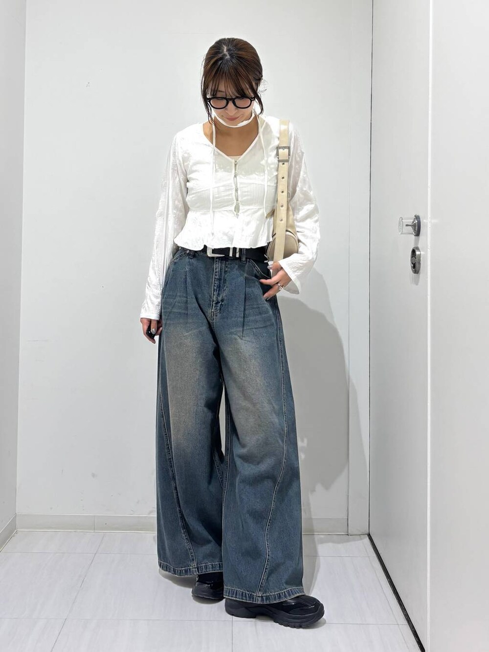 ブルー系のデニムパンツ、ブラック系のスニーカー、ホワイト系のショルダーバッグを着用したレディースの春コーディネートの7枚目の写真
