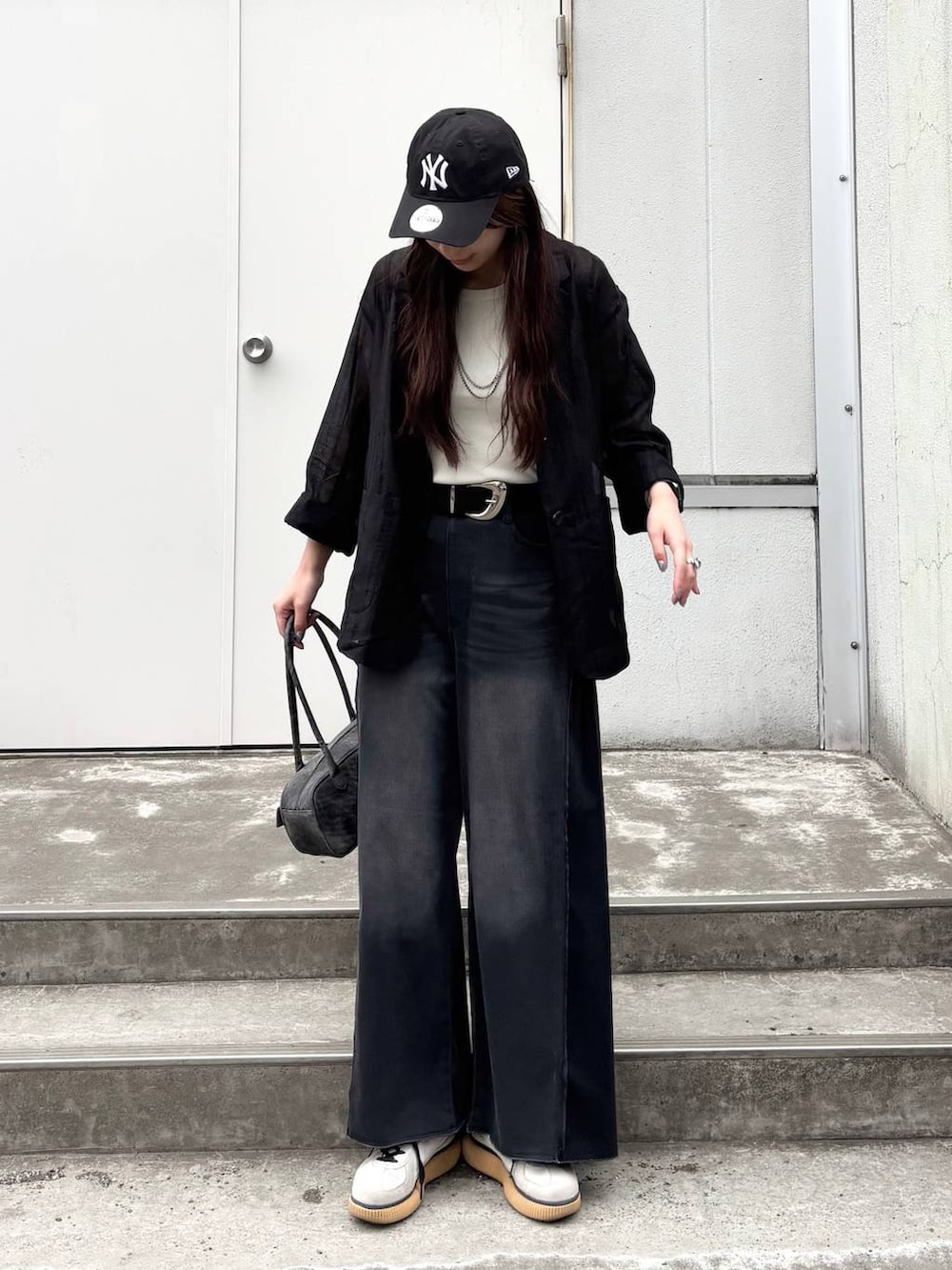 ブラック系のボストンバッグ、ホワイト系のタンクトップ、ブラック系のデニムパンツを着用したレディースの春コーディネートの6枚目の写真