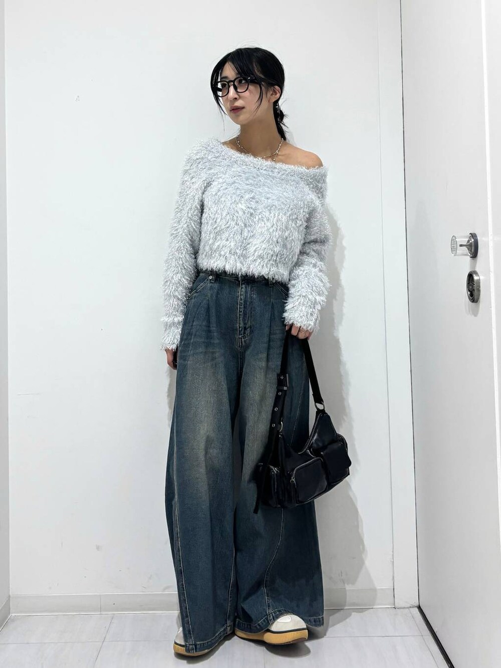 ブルー系のデニムパンツ、ブラック系のショルダーバッグ、ホワイト系のニット/セーターを着用したレディースの秋コーディネートの5枚目の写真