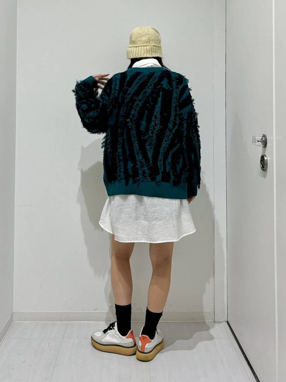 グリーン系のニット/セーター、ブラック系のその他パンツ、ホワイト系のシャツ/ブラウスを着用したレディースの秋コーディネートの5枚目の写真