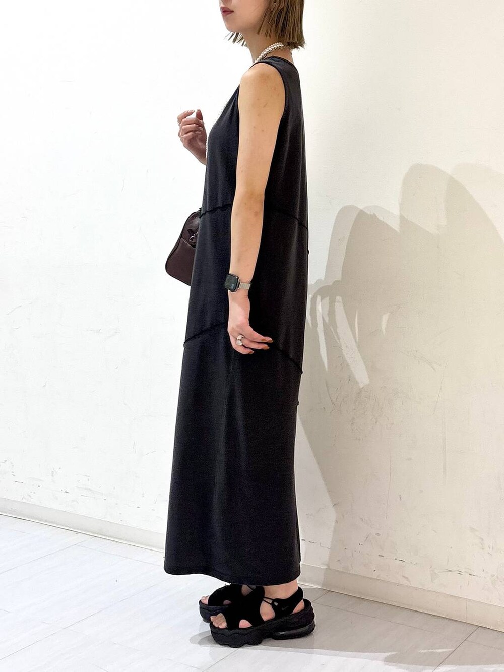 ブラック系のワンピース、ブラウン系のショルダーバッグ、ホワイト系のネックレスを着用したレディースの夏コーディネートの3枚目の写真