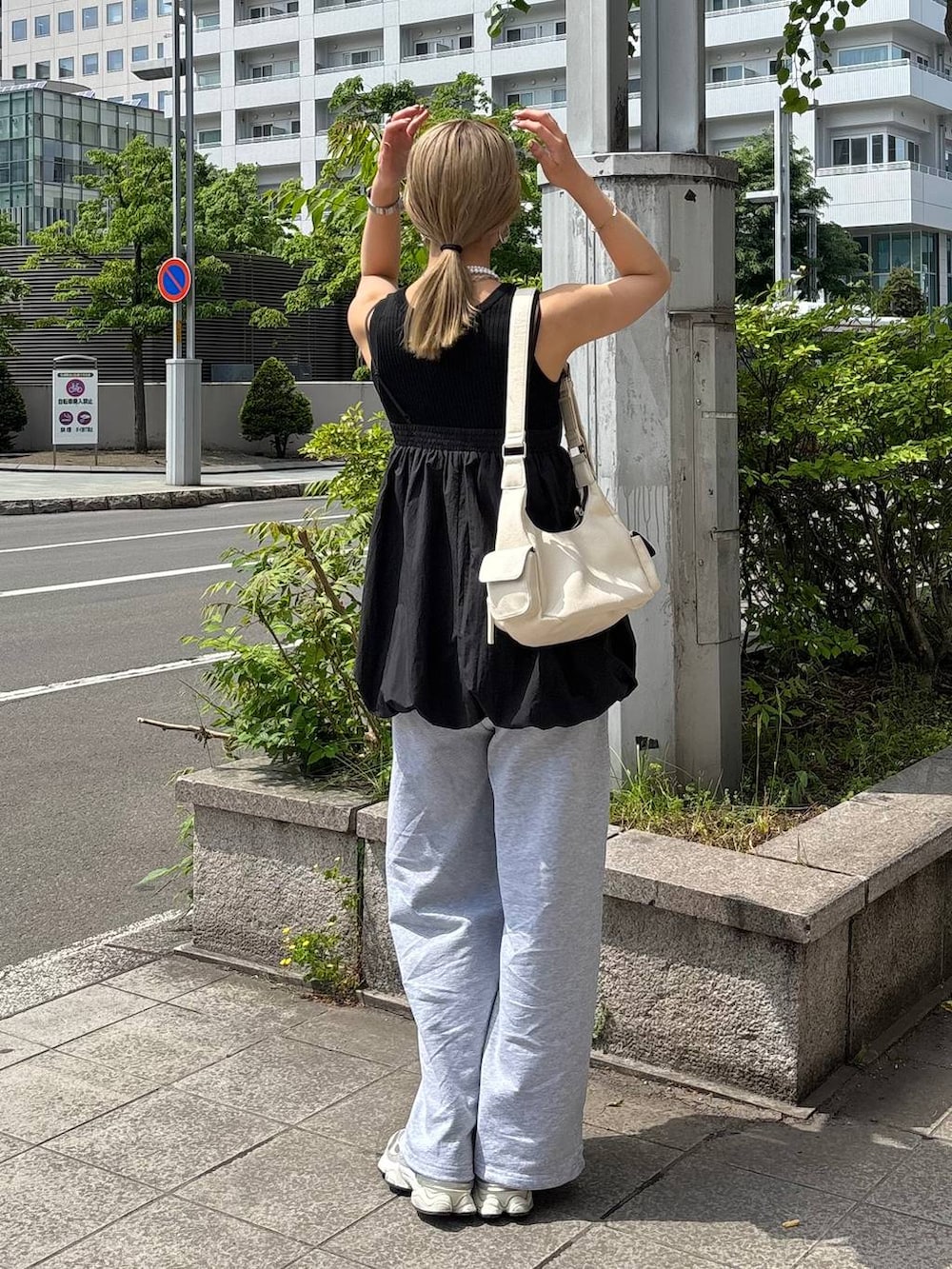 ブラック系のタンクトップ、ホワイト系のショルダーバッグ、グレー系のスウェットパンツを着用したレディースの夏コーディネートの5枚目の写真
