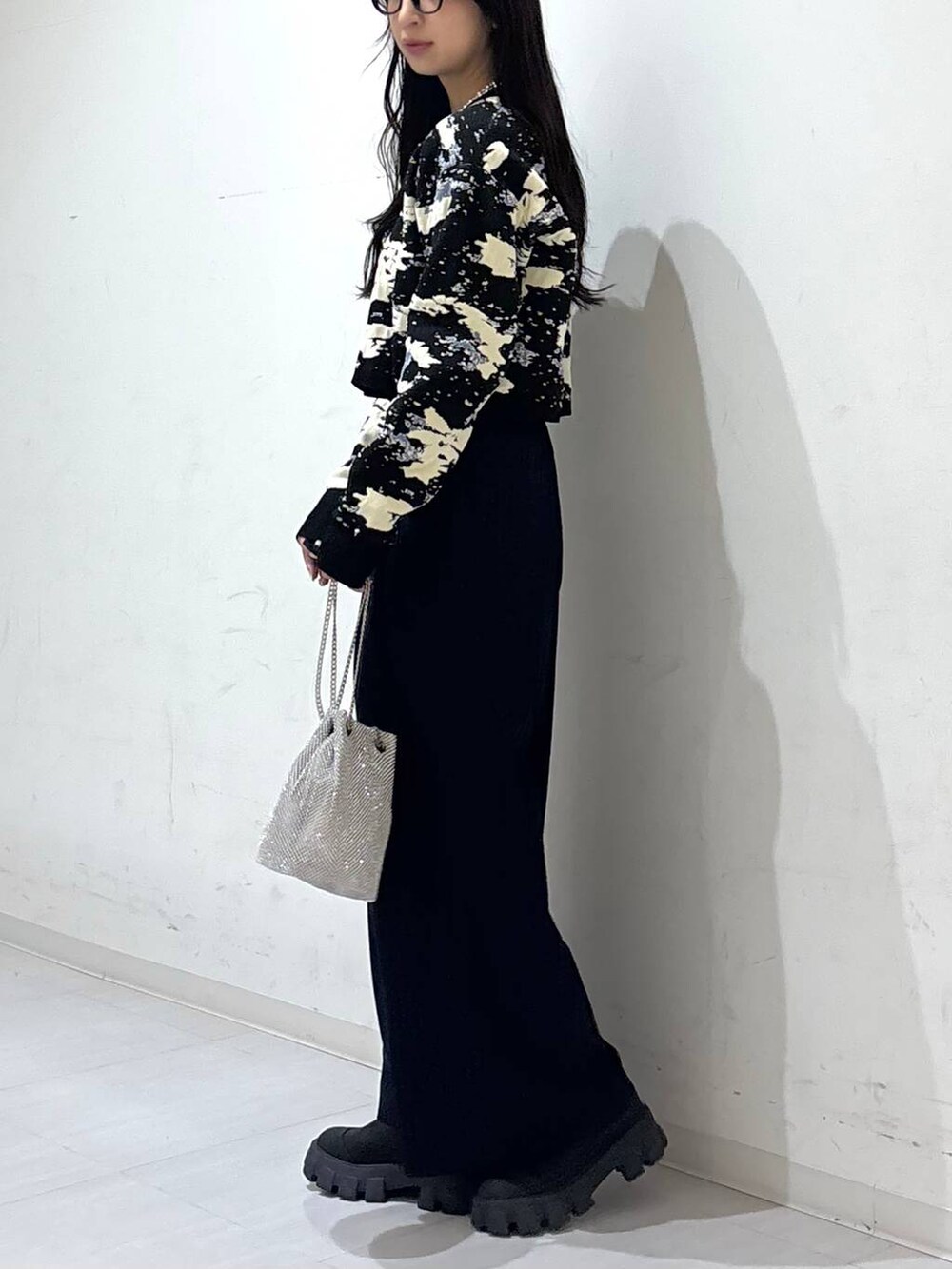 シルバー系のショルダーバッグ、ブルー系のスラックス、ブラック系のニット/セーターを着用したレディースの冬コーディネートの2枚目の写真