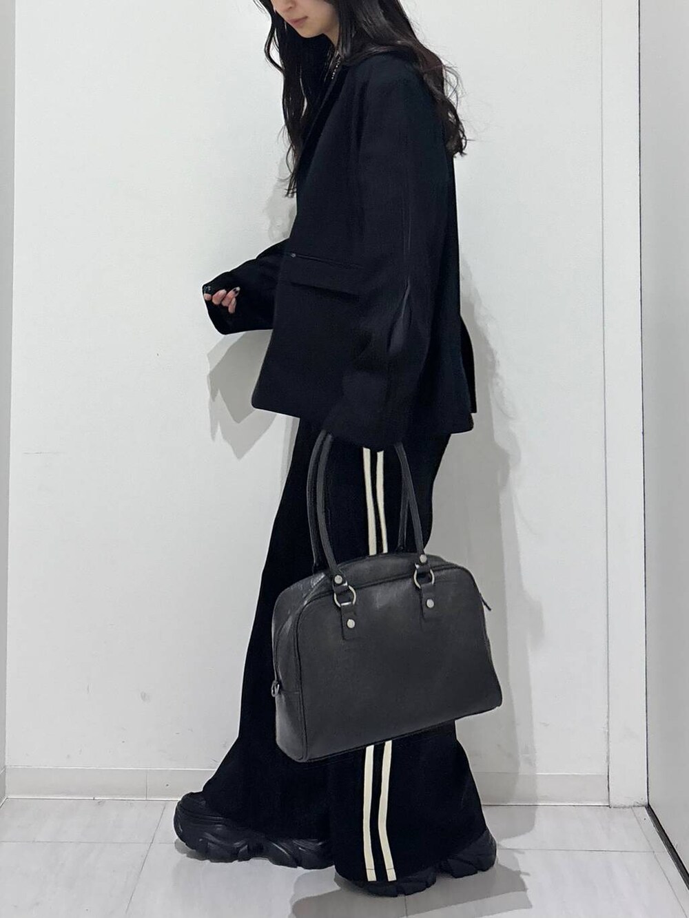 ブラック系のスニーカー、ブラック系のボストンバッグ、ブラック系のテーラードジャケットを着用したレディースの冬コーディネートの3枚目の写真