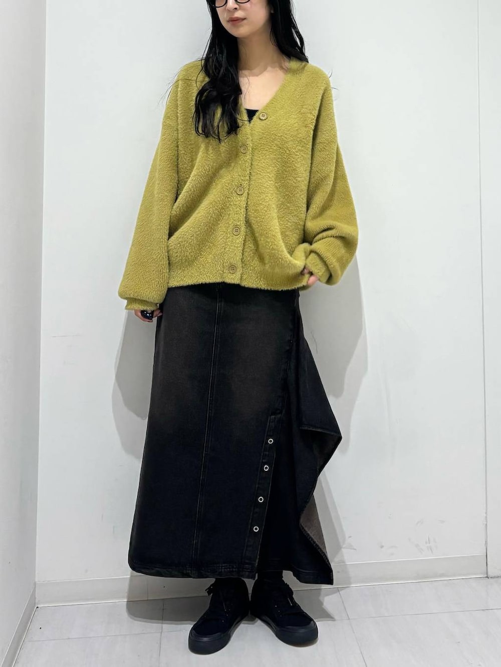 ブラック系のデニムスカート、イエロー系のカーディガン/ボレロを着用したレディースの秋コーディネートの2枚目の写真