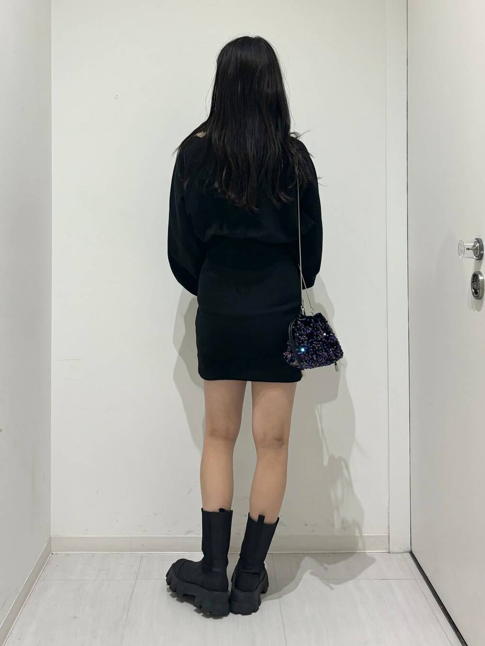 ブラック系のワンピース、ブラック系のブーツ、ブラック系のショルダーバッグを着用したレディースの冬コーディネートの5枚目の写真